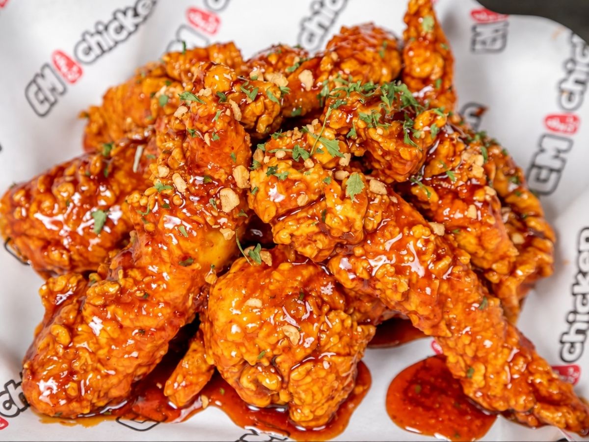 Red-glazed fried chicken with chopped garlic and parsley flakes on printed wrapper paper