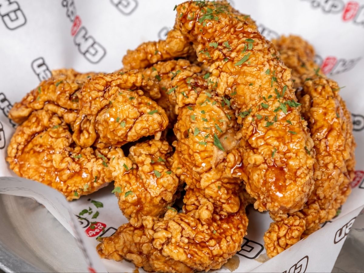 Amber-glazed fried chicken tenders with parsley flakes on a metal tray